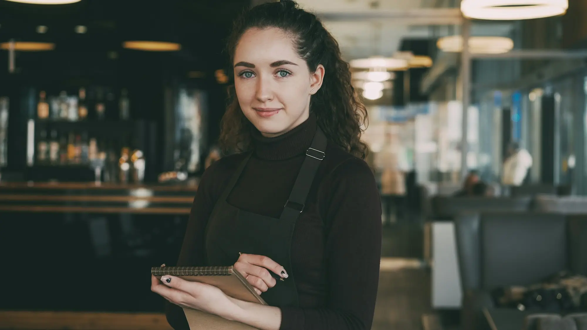 Bakery owner in an apron checking her phone behind the counter