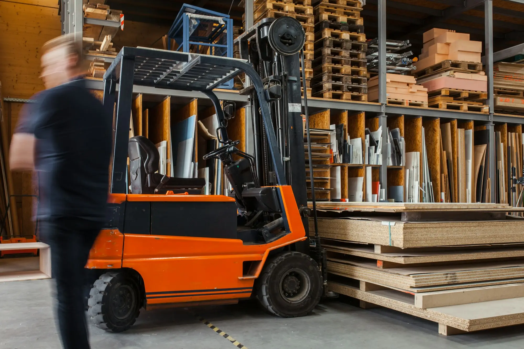 Workshop worker beside a forklift and timber stock